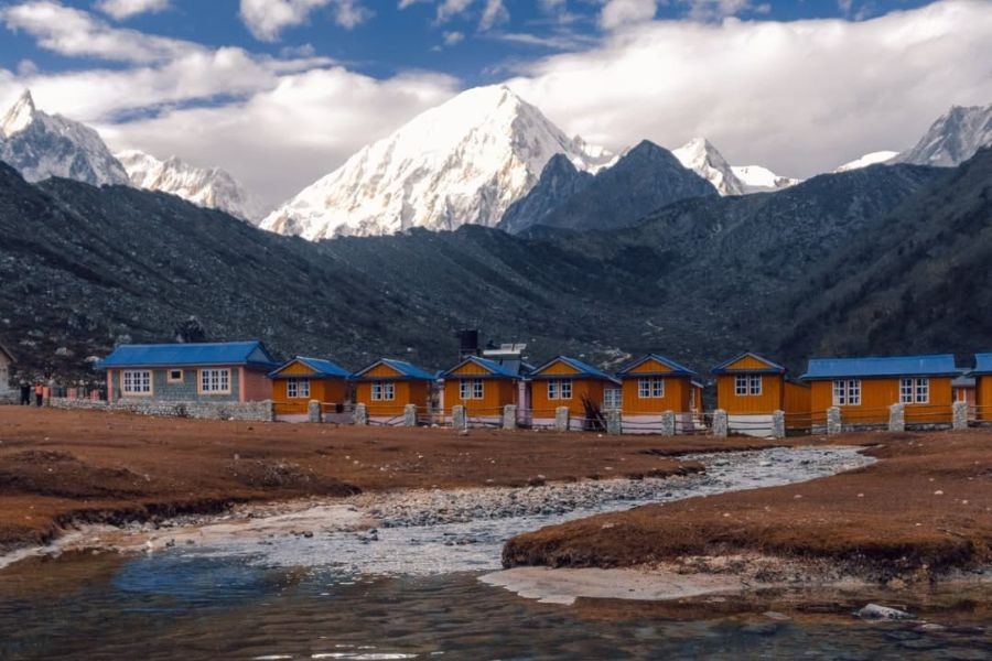 Row of orange teahouses along valley floor with Himalayan mountains behind
