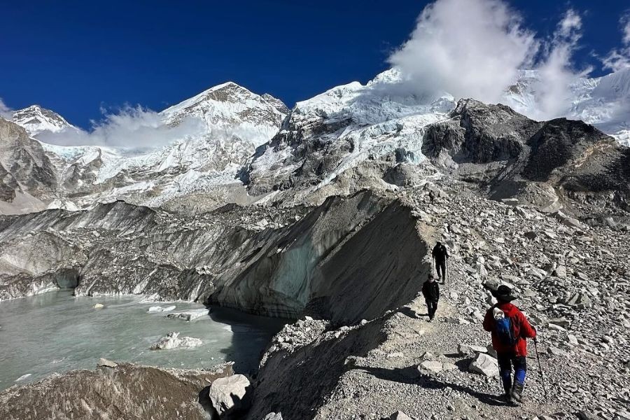 Hikers walking along Everest Base Camp glacier trail with mountain views